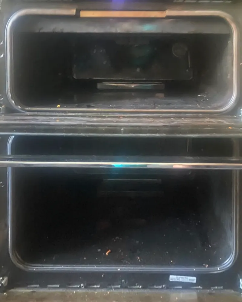 Double oven before cleaning, both doors open, with dark burnt-on grease inside both cavities and on the inner door